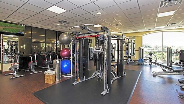 Un gimnasio con equipo de ejercicio variado, incluyendo máquinas de pesas y pesas libres.