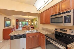 A kitchen with granite countertops, stainless steel appliances, and wooden cabinets. - Westgate Lakes Resort & Spa Universal Studios Area (Orlando)