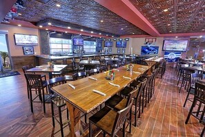 A restaurant with a bar area, multiple tables, and chairs. - Westgate Lakes Resort & Spa Universal Studios Area (Orlando)