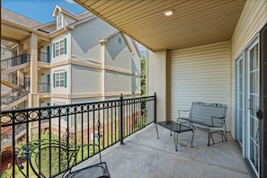 A covered balcony with a metal railing, two metal chairs, and a concrete floor. - 2BR Condo Just Off the Branson Strip (Branson)