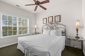 A bedroom with a bed, a ceiling fan, a window with blinds, and two bedside tables with lamps. - 2BR Condo Just Off the Branson Strip (Branson)
