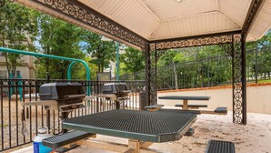 Un área de barbacoa al aire libre con parrillas y mesas de picnic.