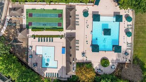 Vista aérea de un resort con una gran piscina, canchas de tenis y zonas de estar al aire libre.
