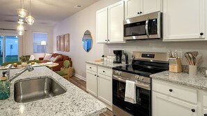 A modern kitchen with white cabinets, stainless steel appliances, and a granite countertop. - Modern 3BR/3BA Family Home - Beach • Pool • Shops (Myrtle Beach)