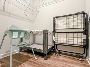 A room with a crib, a baby changing station, and a storage unit with multiple shelves.