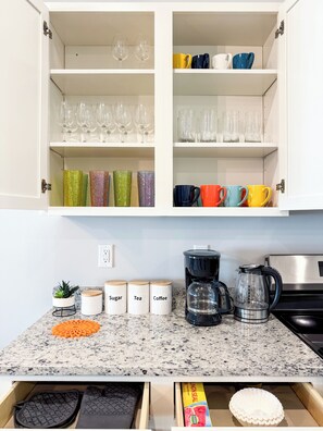 A kitchen with white cabinets, a granite countertop, and various kitchen appliances.