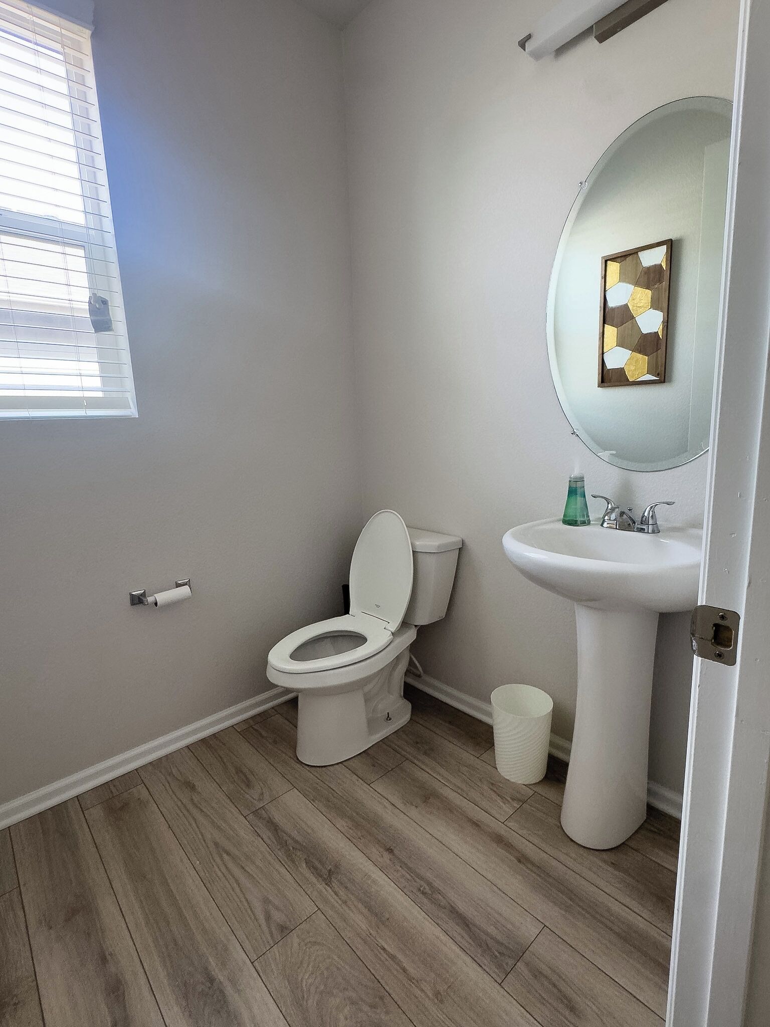 A bathroom with a toilet, sink, and window.
