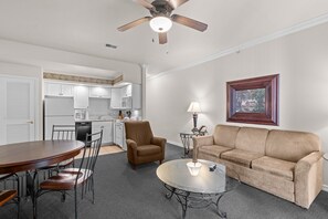 Ein modernes Wohnzimmer mit Essbereich, einer Couch, einem Couchtisch und einem Deckenventilator.