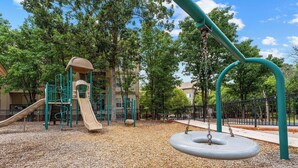 A playground with a slide, swings, and a climbing structure. - French Quarter Resort | Queen Condo | Great Location (Branson)