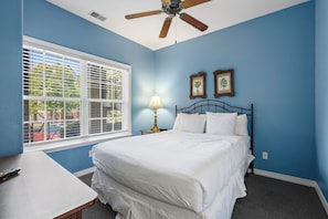 A bedroom with a bed, a nightstand, a lamp, a ceiling fan, and a window with blinds. - Queen Condo Near Shopping & Entertainment (Branson)