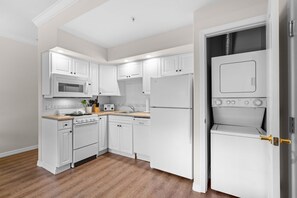 A modern kitchen with white cabinetry, a built-in microwave, a stove, and a refrigerator. - Queen Condo Near Shopping & Entertainment (Branson)