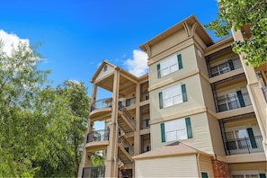 A multi-story residential building with balconies, a central staircase, and a garage. - Stay Close to the Strip | Pet Friendly Queen Condo (Branson)