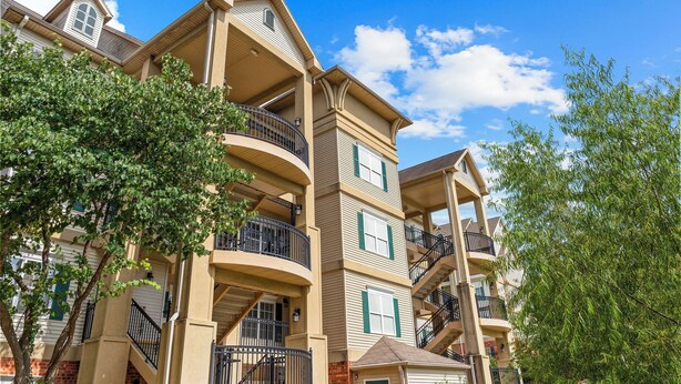 A multi-story residential building with balconies, a brick facade, and a clear blue sky. - Pet Friendly Queen Condo | Pool & Hot Tub (Branson)