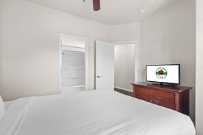 Ein Schlafzimmer mit einem Bett, einem Schminktisch und einem Fernseher, der ein Logo zeigt.