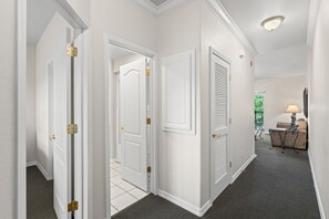 A hallway with white walls, a carpeted floor, and doors with brass hinges. - Resort Queen Condo | Balcony • Pool • Hot Tub (Branson)