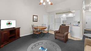 A living room with a television, a dining table, and a ceiling fan. - Relax at French Quarter Resort | Queen Condo (Branson)