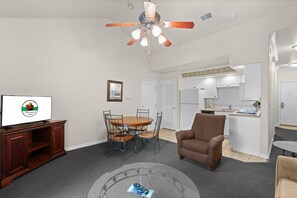A living room with a television, a dining table, and a ceiling fan. - Relax at French Quarter Resort | Queen Condo (Branson)