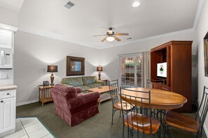 A dining area with a wooden table and chairs, a ceiling fan, and a television. - King Suite | Pet Friendly | Resort Pool & Hot Tub (Branson)