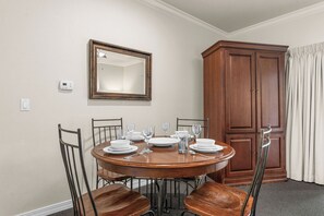 Ein Esszimmer mit einem runden Tisch für vier Personen, einem Holzschrank und einem an der Wand befestigten Spiegel.