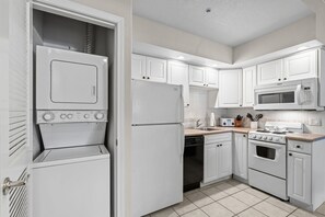 A kitchen with white cabinets, a microwave, a stove, and a dishwasher. - Pet Friendly King Condo • Pool • Hot Tub (Branson)
