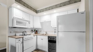 A kitchen with white cabinets, a microwave, a stove, a dishwasher, and a refrigerator. - Relaxing King Condo | Close to Shows & Attractions (Branson)