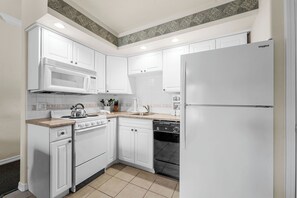 A kitchen with white cabinets, a microwave, a stove, a dishwasher, and a refrigerator. - Relaxing King Condo | Close to Shows & Attractions (Branson)