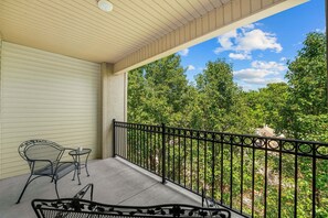 A covered balcony with a metal railing, a chair, and a small table. - Relaxing King Condo | Close to Shows & Attractions (Branson)