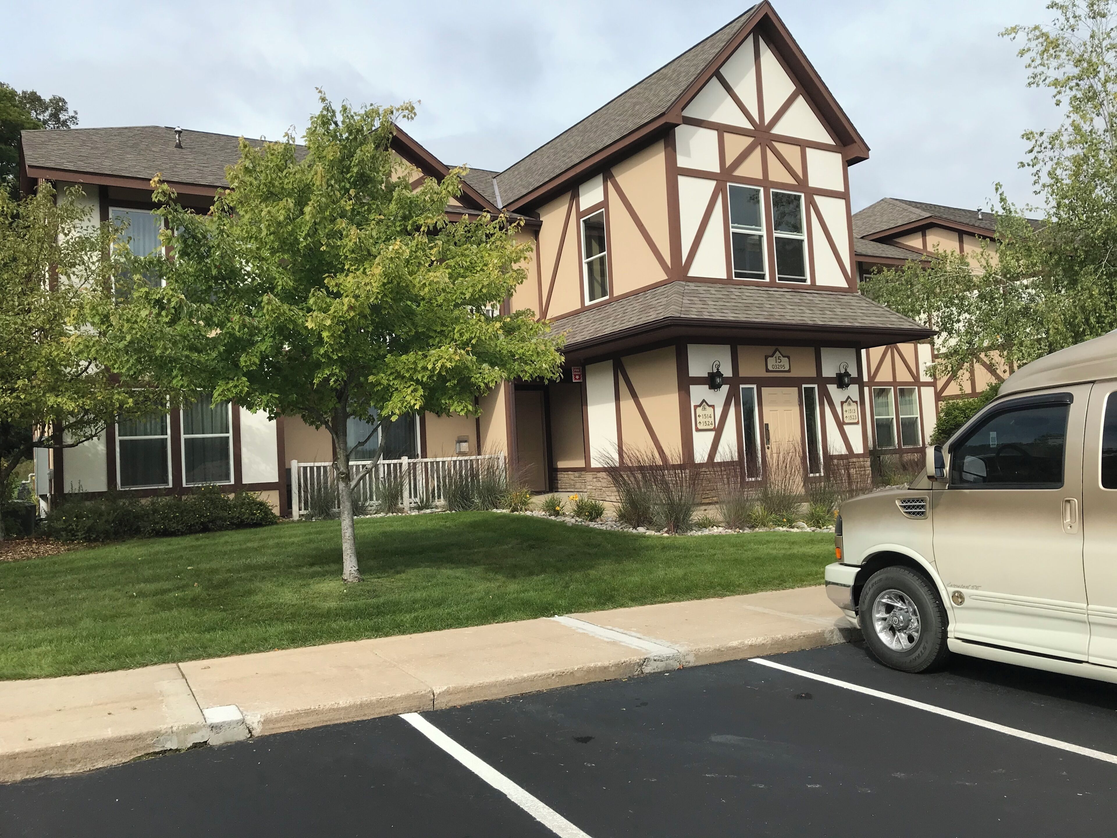 Un bâtiment à deux étages avec une façade de style Tudor, un parking et un arbre au premier plan.