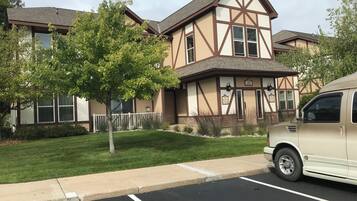 Un bâtiment à deux étages avec une façade de style Tudor, un parking et un arbre au premier plan.
