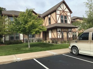 Un bâtiment à deux étages avec une façade de style Tudor, un parking et un arbre au premier plan.
