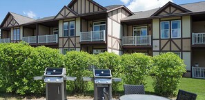 Un immeuble à plusieurs étages doté de balcons et d’un espace barbecue avec deux grils.