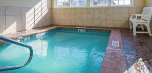 Une piscine dotée d’une terrasse carrelée, d’un banc et d’une fenêtre laissant entrer la lumière naturelle.
