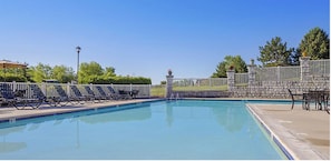 Una piscina con un muro de piedra y una valla metálica.