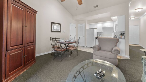 A spacious living area with a dining table, chairs, a sofa, a glass coffee table, and a ceiling fan. - King Suite | Pet Friendly | Resort Pool & Hot Tub (Branson)