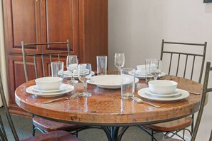 A round dining table with white plates, glasses, and cutlery, surrounded by metal chairs. - King Suite | Pet Friendly | Resort Pool & Hot Tub (Branson)