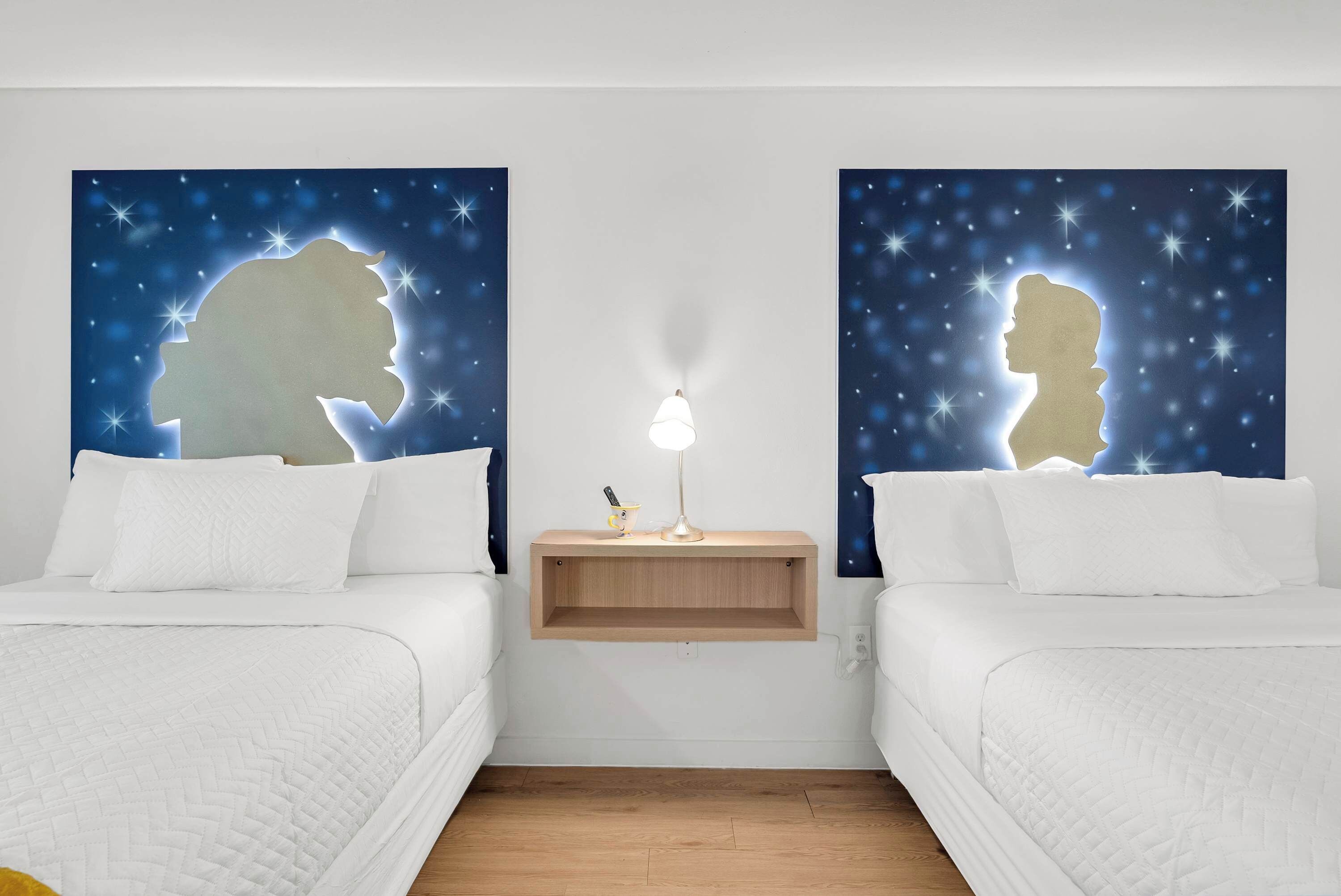 Een slaapkamer met twee bedden, een nachtkastje, een lamp en wanddecoratie met sterren.