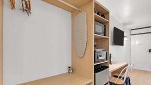 Eine kleine Küche mit integriertem Mikrowellenherd, einer Kaffeemaschine und einem Kühlschrank.