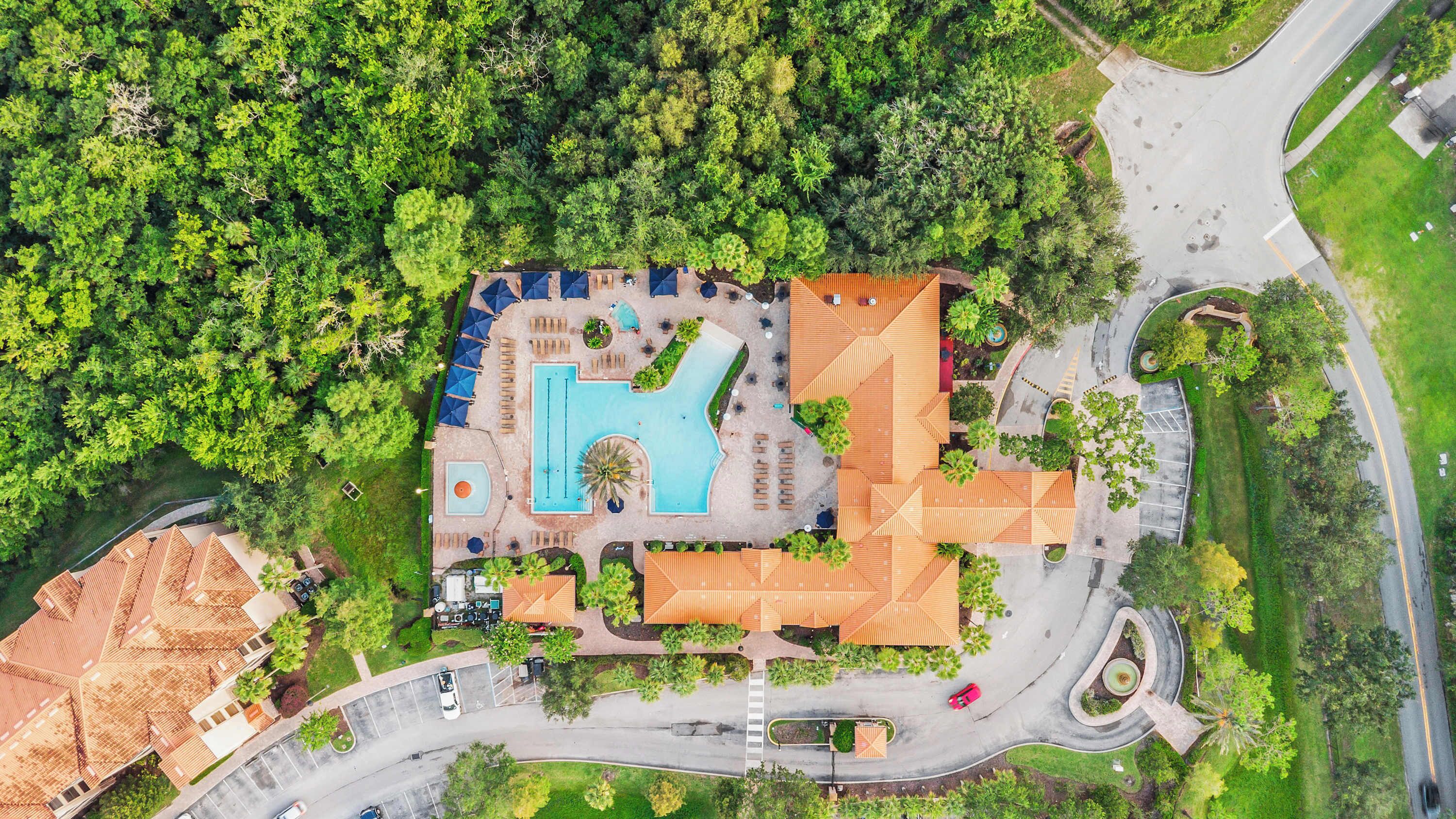 An aerial view of a resort with a swimming pool, multiple buildings, and a road network.
