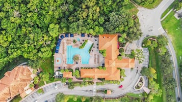 An aerial view of a resort with a swimming pool, multiple buildings, and a road network.