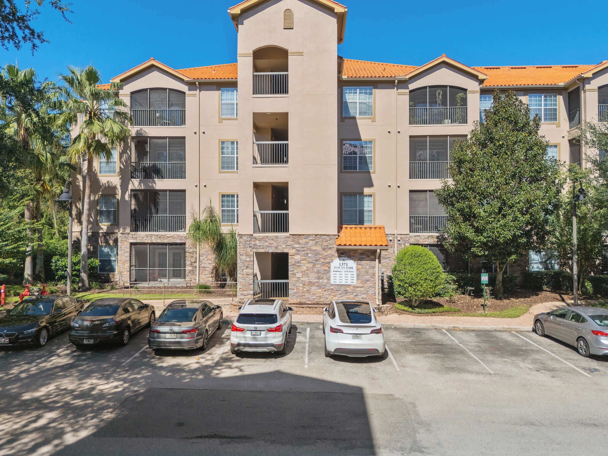 Exterior view of a modern apartment building with covered balconies and parking spaces.