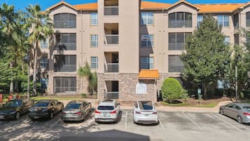 Exterior view of a modern apartment building with covered balconies and parking spaces.