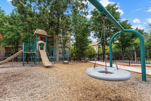 Ein Spielplatz mit Rutsche, Schaukeln und einer Kletterkonstruktion.