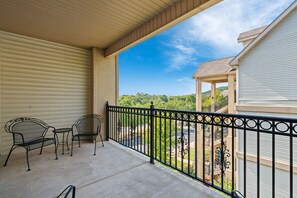 Ein Balkon mit Blick auf ein Wohngebiet, eine überdachte Sitzecke mit Stühlen und ein Metallgeländer.