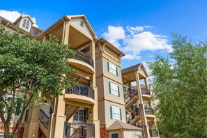 A multi-story residential building with balconies, a brick facade, and a clear blue sky. - Cozy King Retreat | Great Location | Pet Friendly (Branson)