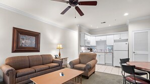 A living room with a sofa, armchair, coffee table, and a ceiling fan. - French Quarter King Getaway | Pet Friendly Resort (Branson)