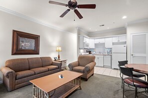 A living room with a sofa, armchair, coffee table, and a ceiling fan. - French Quarter King Getaway | Pet Friendly Resort (Branson)