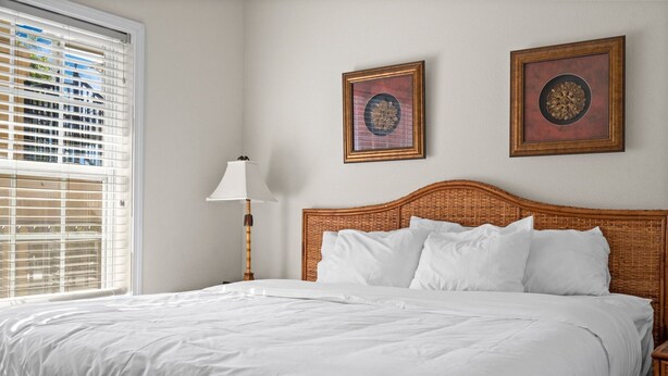 A neatly made bed with white linens in a room with a large window and two framed pictures on the wall. - French Quarter King Getaway | Pet Friendly Resort (Branson)