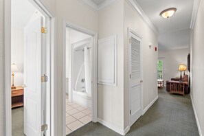 Ein Flur mit weißen Türen, einer Dusche, einer Sitzecke mit Tisch und Stühlen sowie einer Deckenleuchte.