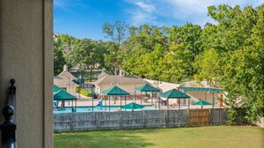 Ein Garten mit Swimmingpool, Sonnenschirmen und Liegestühlen.