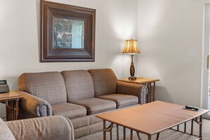A living room with a sofa, a table, a lamp, and a framed picture on the wall. - King Condo Near Silver Dollar City & Highway 76 (Branson)